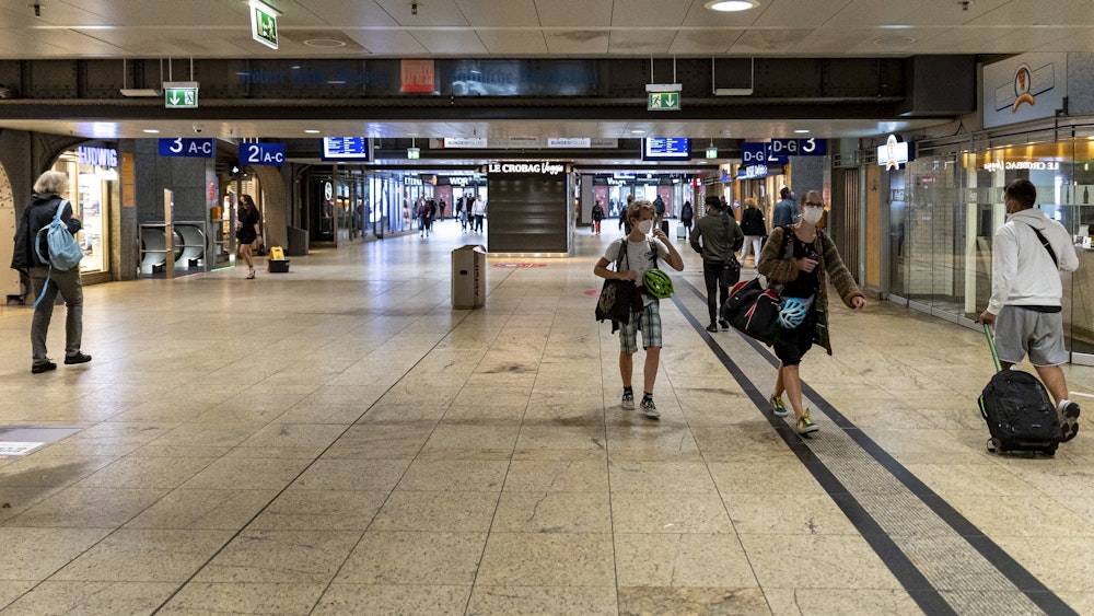 Menschen mit Gepäck gehen durch den Kölner Hauptbahnhof.