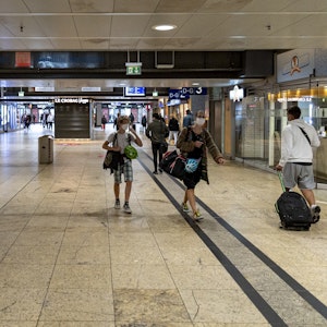 Menschen mit Gepäck gehen durch den Kölner Hauptbahnhof.