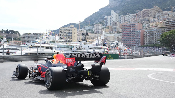 Ein Formel-1-Rennauto fährt durch Monaco. Im Hintergrund sind Yachten und Häuser zu sehen.