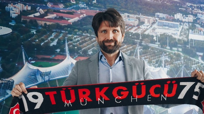 Trainer Peter Hyballa hält einen Schal seines neuen Vereins Türkgücü München hoch.