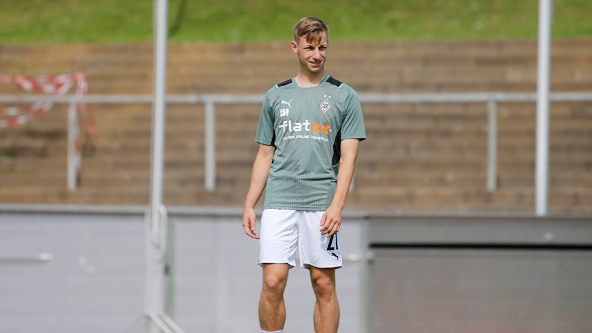 Luiz Skraback von Borussia Mönchengladbach, hier am 21. August 2021, steht lachend mit dem Ball am Fuß auf dem Fußballplatz.