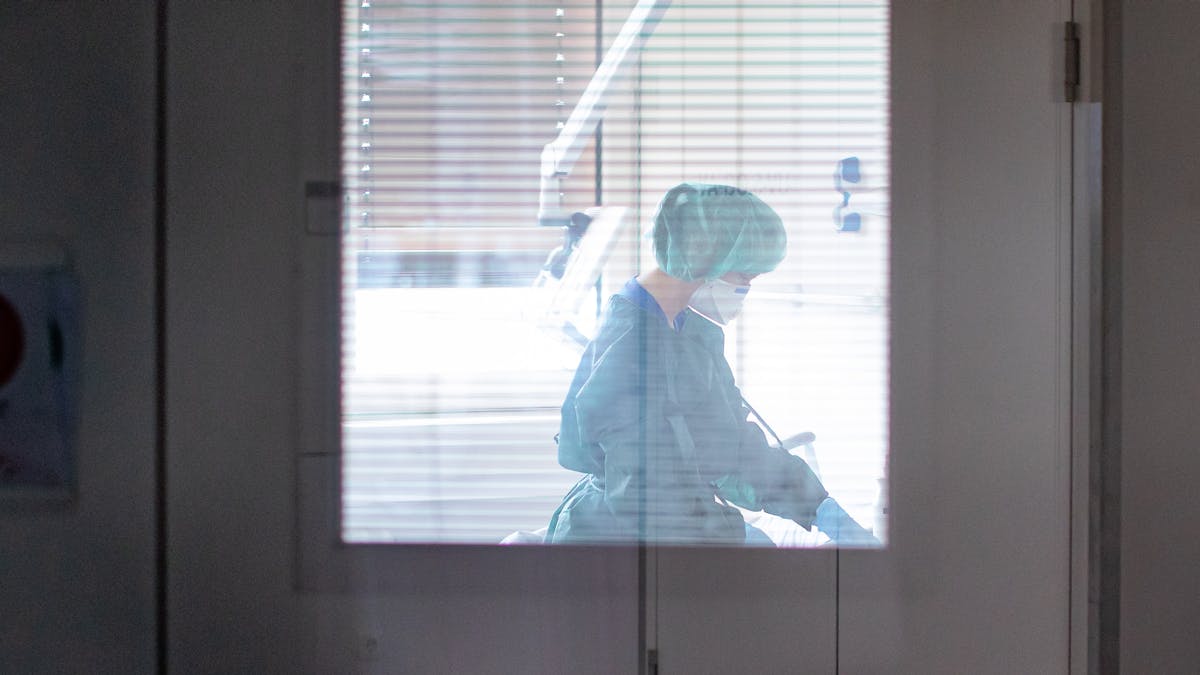 Eine Krankenschwester auf der Infektionsstation der Uniklinik Essen versorgt in Schutzkleidung und mit einer Atemmaske einen Patienten.&nbsp;