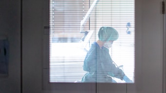 Eine Krankenschwester auf der Infektionsstation der Uniklinik Essen versorgt in Schutzkleidung und mit einer Atemmaske einen Patienten.