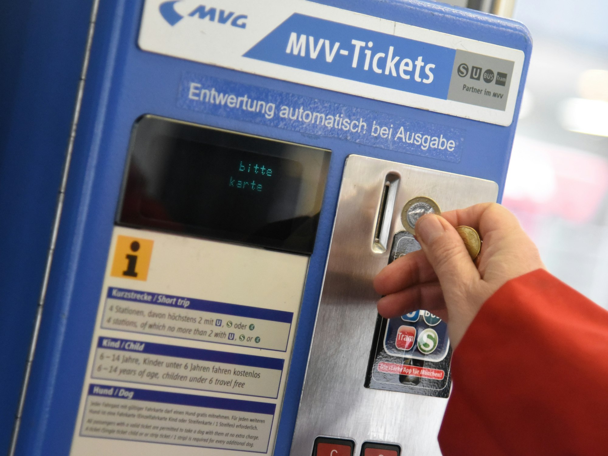 Eine Person wirft Münzen in einen Automaten desMünchner Verkehrs- und Tarifverbunds