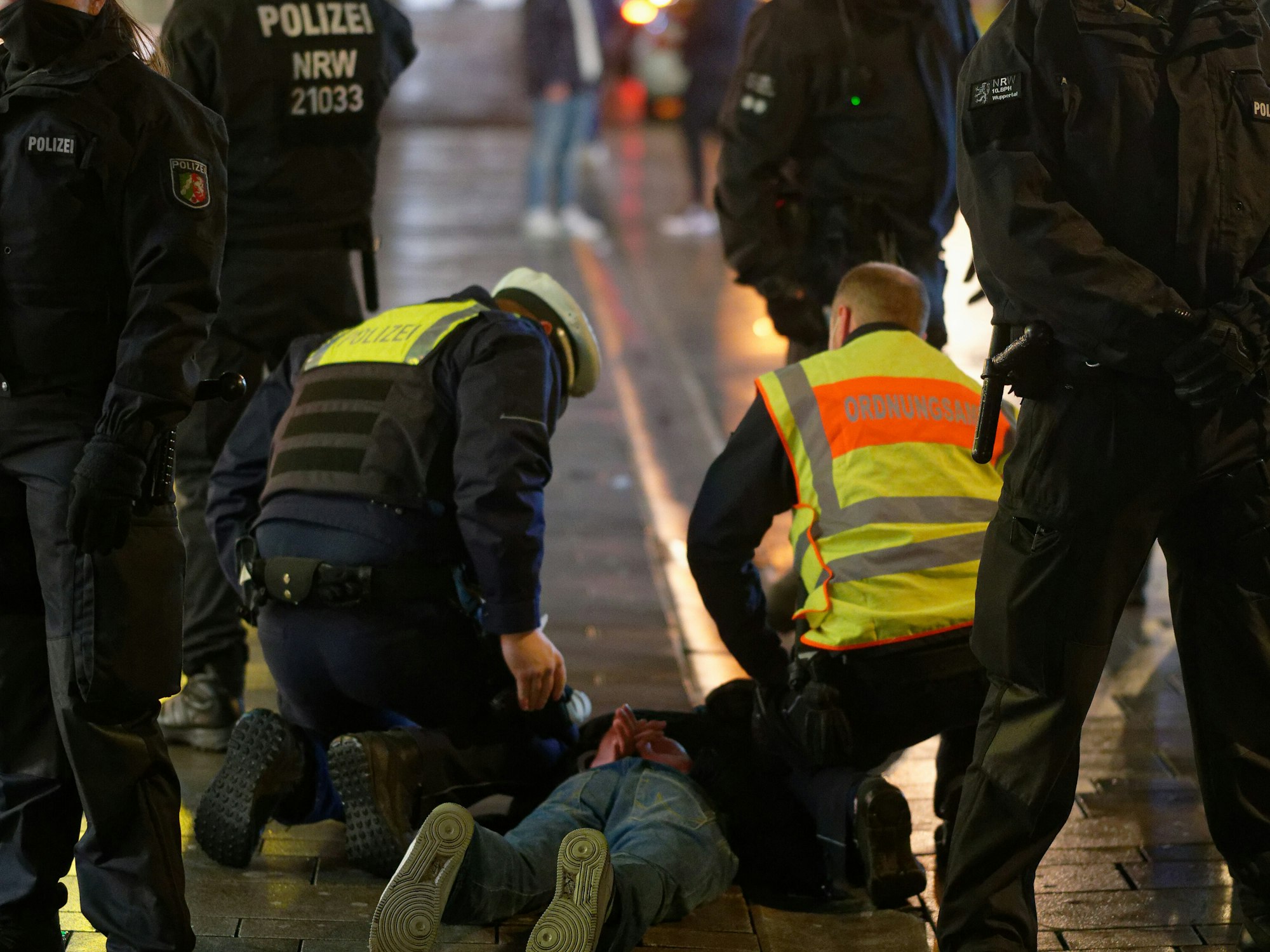 Mitarbeiter des Ordnungsamtes und der Polizei halten am 12. Dezember 2020 in der Düsseldorfer Altstadt einen bei einer Kontrolle Geflüchteten auf dem Boden fest.