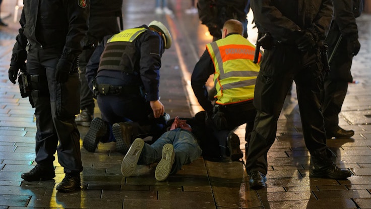 Mitarbeiter des Ordnungsamtes und der Polizei halten am 12. Dezember 2020 in der Düsseldorfer Altstadt einen bei einer Kontrolle Geflüchteten auf dem Boden fest.
