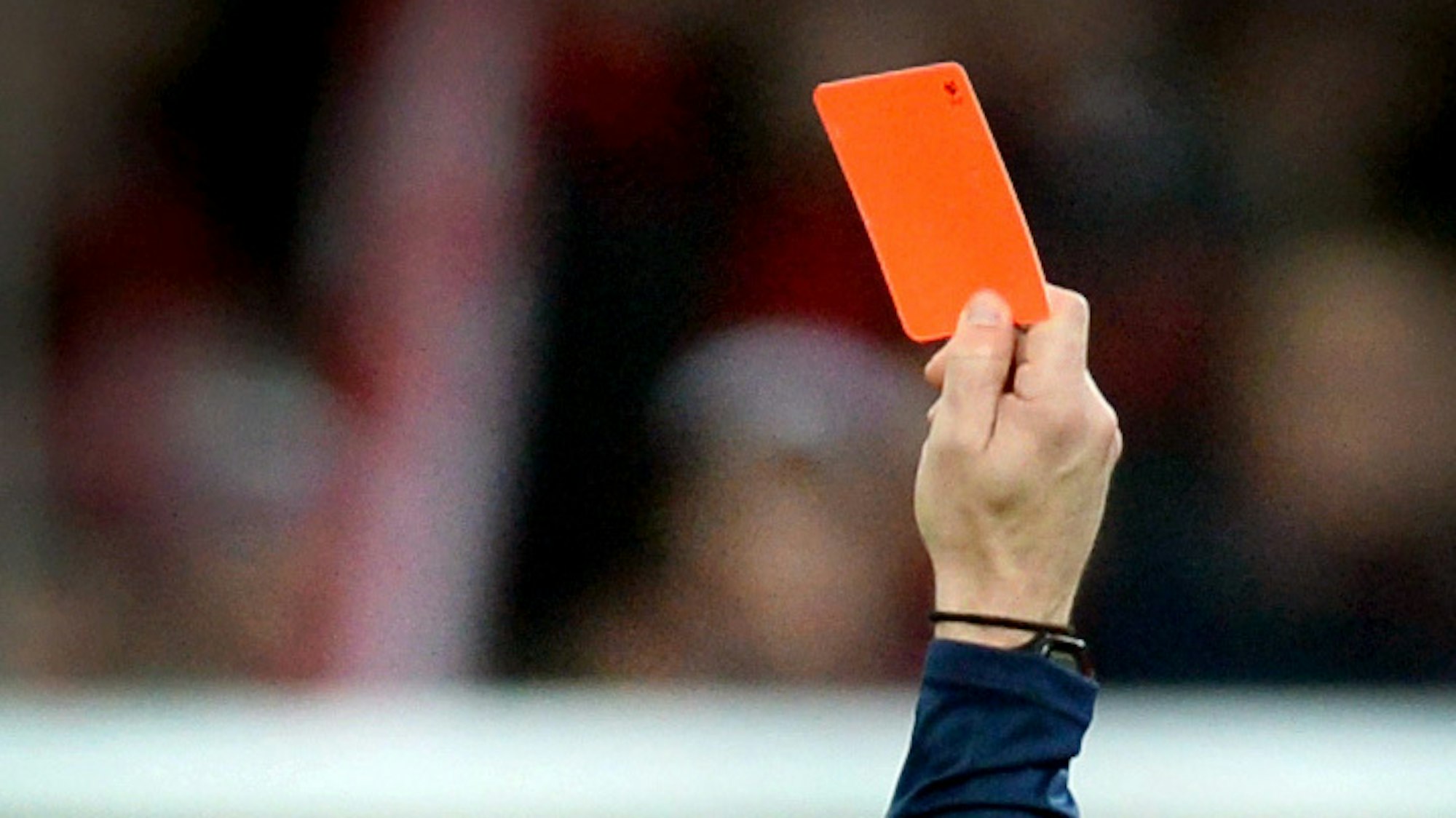 Ein Schiedsrichter zeigt einem Fußballspieler die Rote Karte.