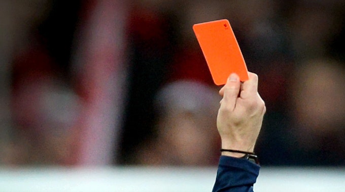 Ein Schiedsrichter zeigt einem Fußballspieler die Rote Karte.
