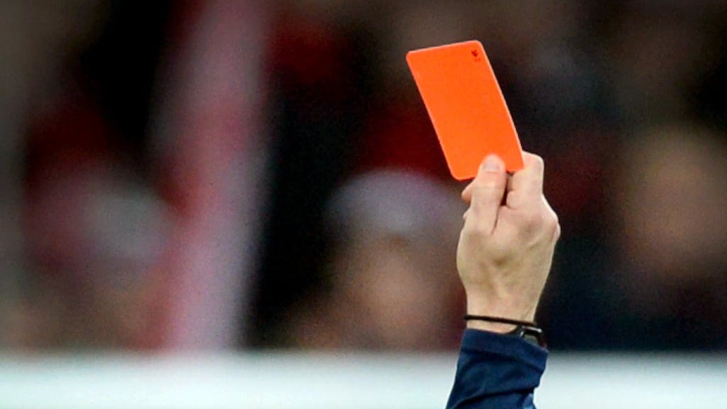 Ein Schiedsrichter zeigt einem Fußballspieler die rote Karte.