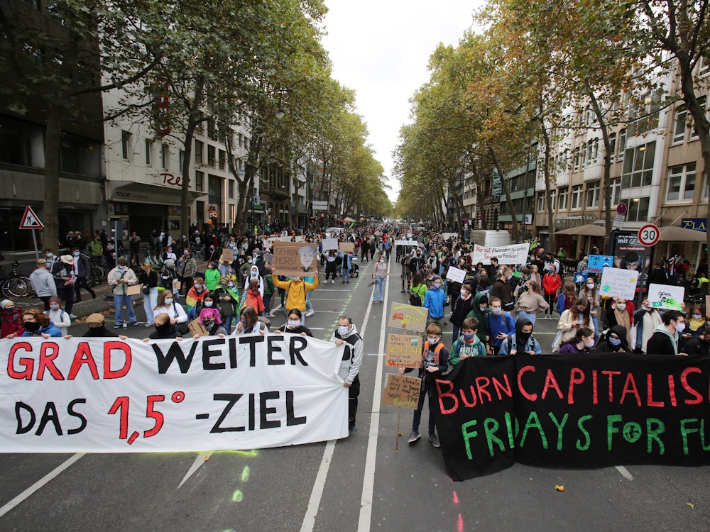 Hinter zwei großen Bannern stehe tausende Demonstranten einer Fridays for Future Demo.