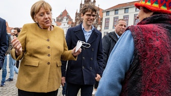 Bundeskanzlerin Angela Merkel (l., CDU) und Georg Günther (CDU), Vorsitzender der Jungen Union Mecklenburg-Vorpommerns, bei einem Überraschungsbesuch auf dem Wochenmarkt von Greifswald. Merkel spricht mit der Blumenhändlerin Edeltraud Honig, es sind schöne Worte des Abschieds.
