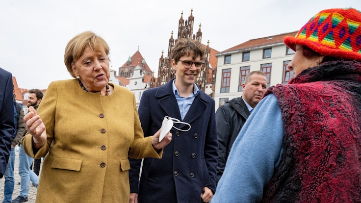 Bundeskanzlerin Angela Merkel (l., CDU) und Georg Günther (CDU), Vorsitzender der Jungen Union Mecklenburg-Vorpommerns, bei einem Überraschungsbesuch auf dem Wochenmarkt von Greifswald. Merkel spricht mit der Blumenhändlerin Edeltraud Honig, es sind schöne Worte des Abschieds.