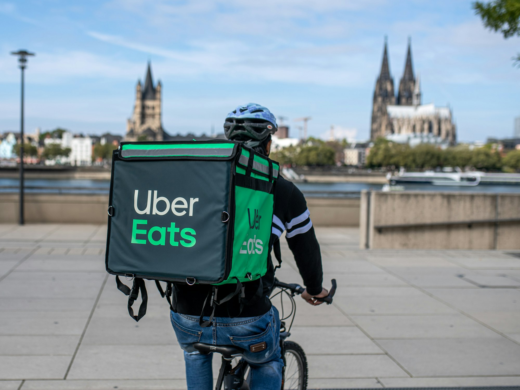 Ein Radfahrer mit großer Essenstasche von Uber Eats auf dem Rücken.
