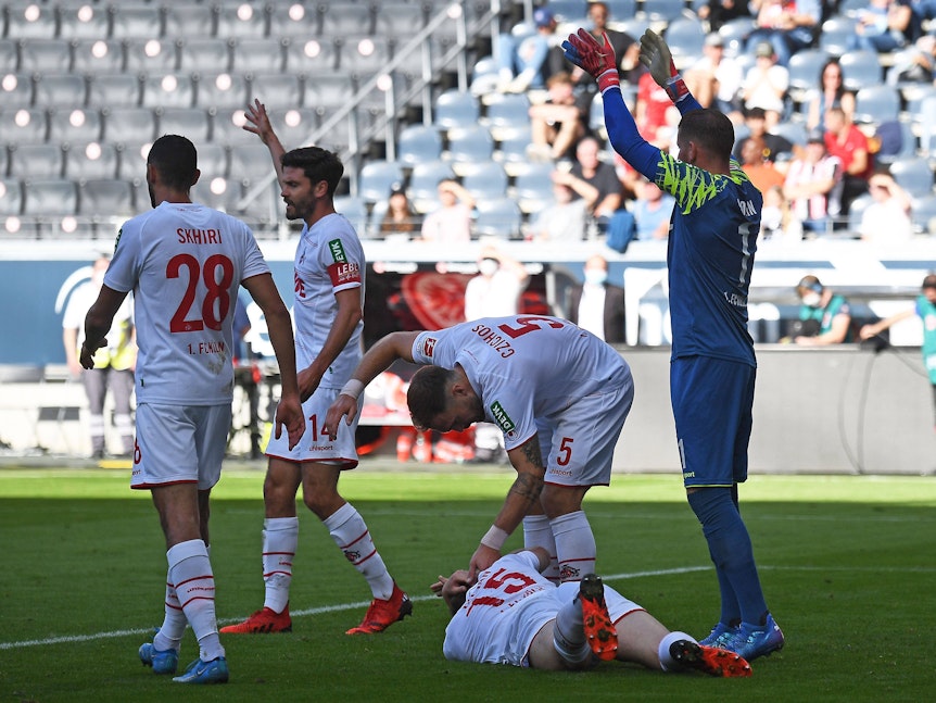 Luca Kilian liegt beim Spiel Eintracht Frankfurt gegen 1. FC Köln auf dem Rasen.