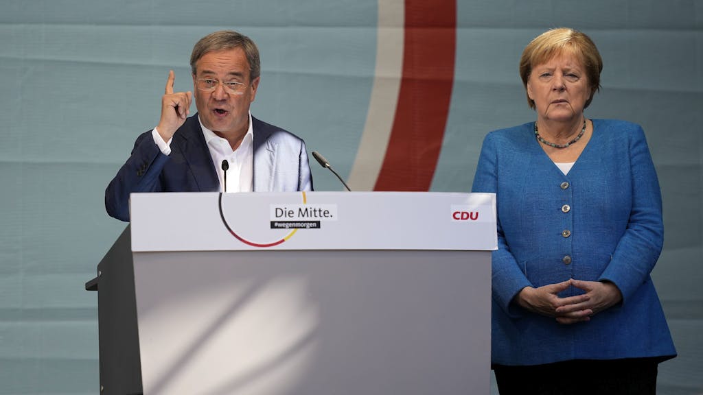 CDU-Kanzlerkandidat Armin Laschet und Noch-Kanzlerin Angela Merkel bei ihrem gemeinsamen Wahlkampfauftritt am Samstag, 25. September, in Aachen. Laschet spricht ins Mikro, Merkel steht daneben.