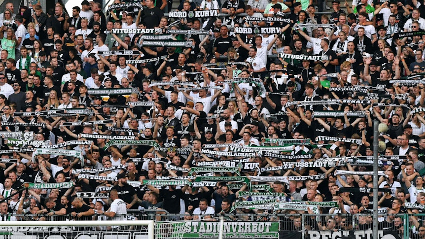 Moenchengladbach's fans display their scarves prior to the German first division Bundesliga football match Borussia Moenchengladbach v BVB Borussia Dortmund in Moenchengladbach, western Germany, on September 25, 2021. (Photo by UWE KRAFT / AFP) / DFL REGULATIONS PROHIBIT ANY USE OF PHOTOGRAPHS AS IMAGE SEQUENCES AND/OR QUASI-VIDEO