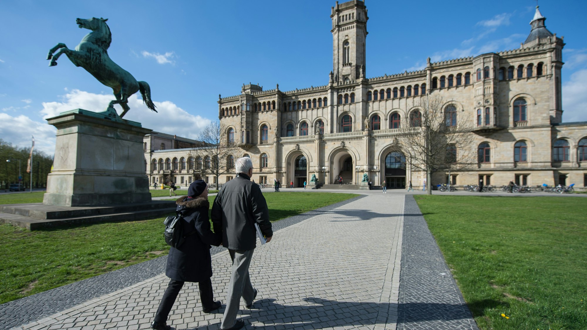 Zwei Passanten gehen auf einem Fußweg zur Leibniz Universität.