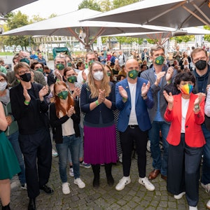 Die Direktkandidaten der Grünen Katharina Dröge und Sven Lehmann stehen im Kreise mit anderen Parteimitgliedern und applaudieren.