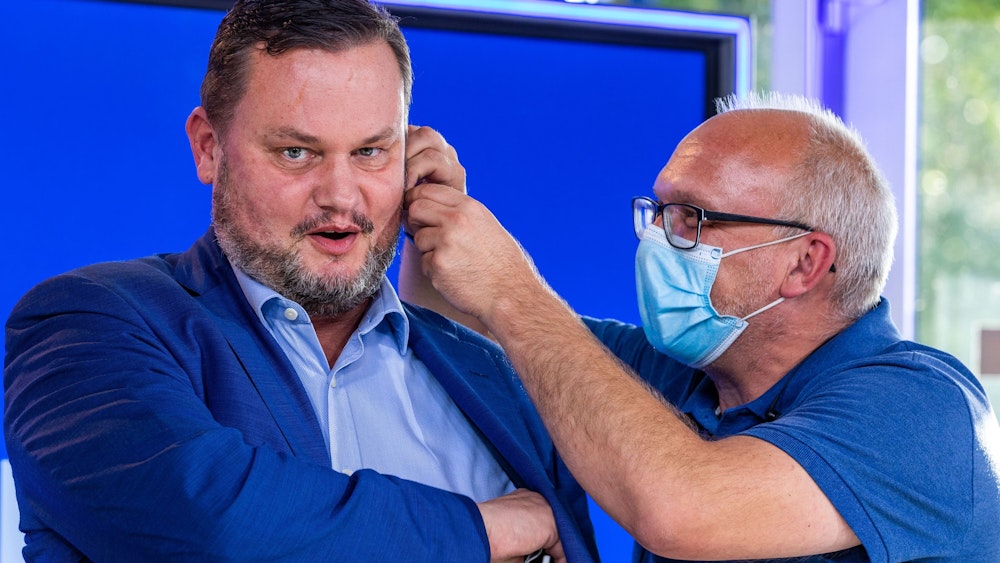 Rene Domke, Spitzenkandidat der FDP für die Landtagswahl in Mecklenburg-Vorpommern, am 14. September vor einem Rededuell des NDR. Ein Mitarbeiter steckt ihm einen Knopf ins Ohr.