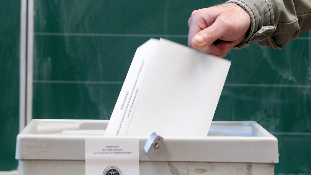 Ein Wähler wirft seinen Stimmzettel am 26. September 2021 in einem Wahllokal in die Wahlurne in Duisburg.