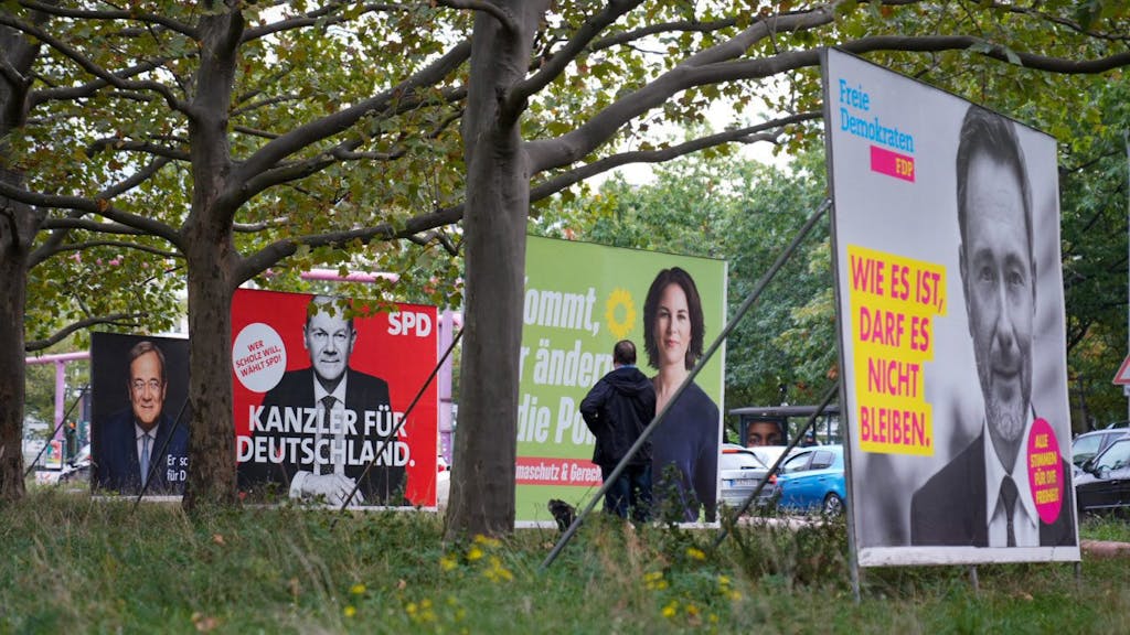 Wahlplakate der SPD mit Olaf Scholz, von Bündnis 90/Die Grünen mit Annalena Baerbock und der FDP mit Christian Lindner stehen auf einer Straße nebeneinander.