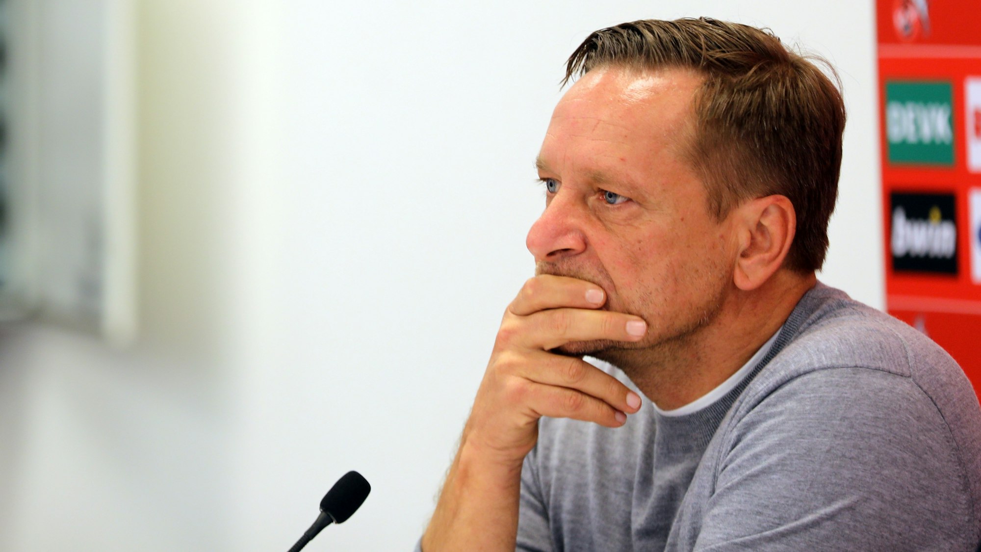 Horst Heldt fährt sich bei einer Pressekonferenz des 1. FC Köln mit den Händen durch das Gesicht.