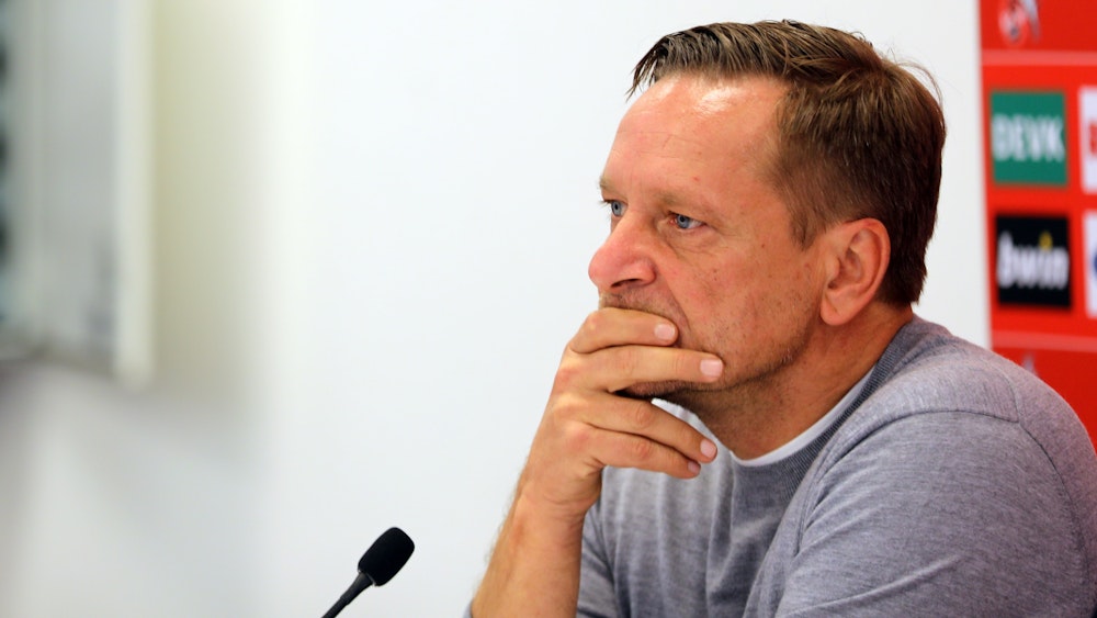 Horst Heldt fährt sich bei einer Pressekonferenz des 1. FC Köln mit den Händen durch das Gesicht.