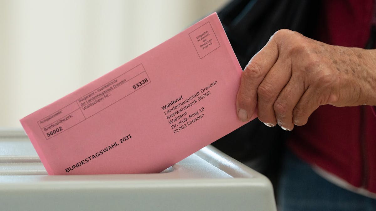 Eine Frau wirft in einem Briefwahlbüro ihren Wahlschein in einer Wahlurne.&nbsp;