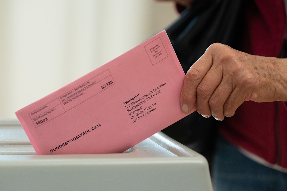Eine Frau wirft in einem Briefwahlbüro ihren Wahlschein in einer Wahlurne.