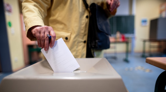 Eine Frau wirft einen Wahlschein in eine Wahlurne.