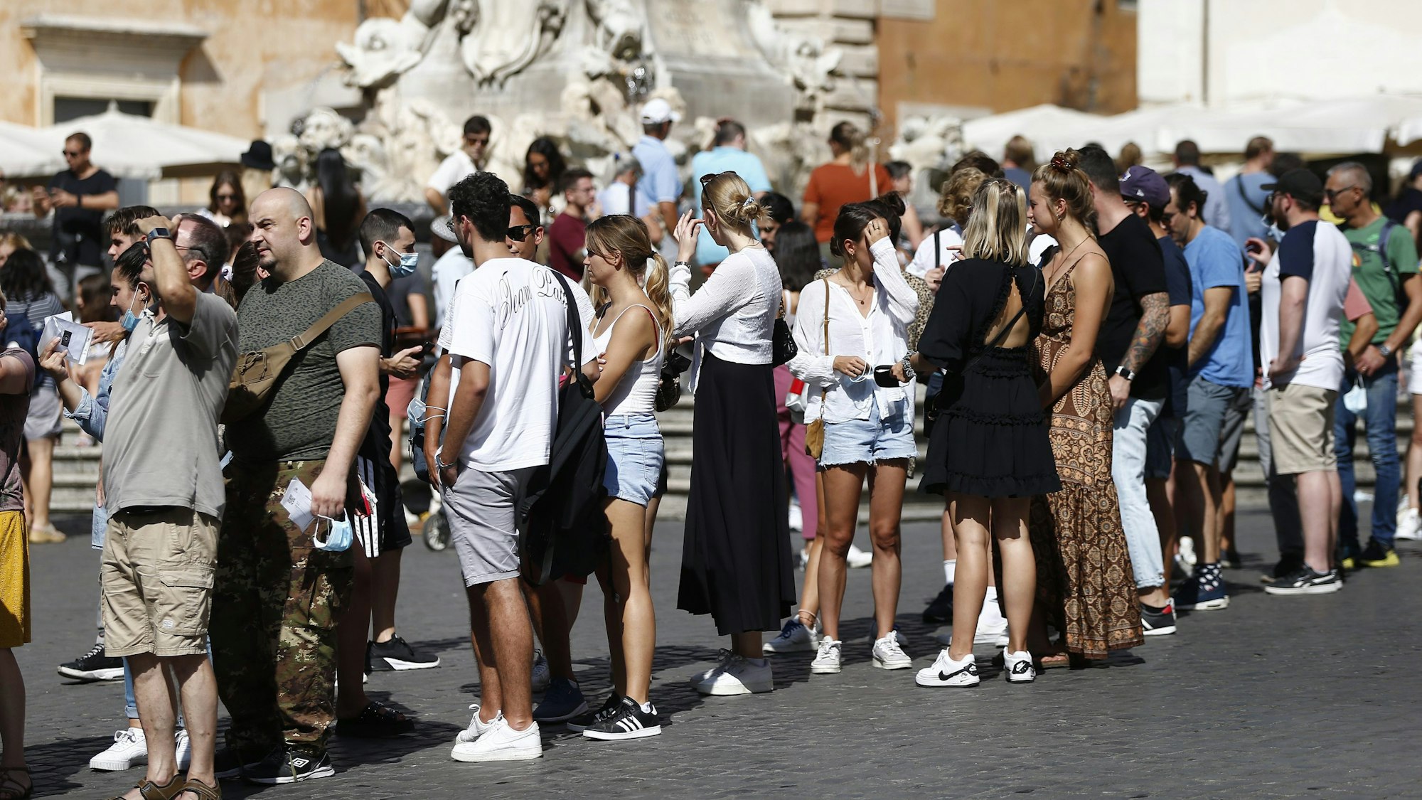 Touristen stehen in einer Schlange und warten darauf, das Pantheon zu besichtigen. Kaum einer der abgebildeten Personen trägt einen Mund-Nasen-Schutz.