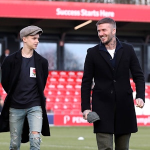 Romeo Beckham und David Beckham gehen auf dem Fußballplatz entlang.