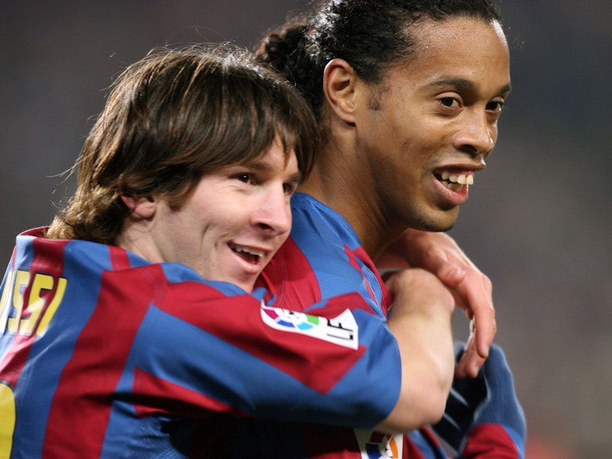 Lionel Messi umarmt Ronaldinho von hinten.