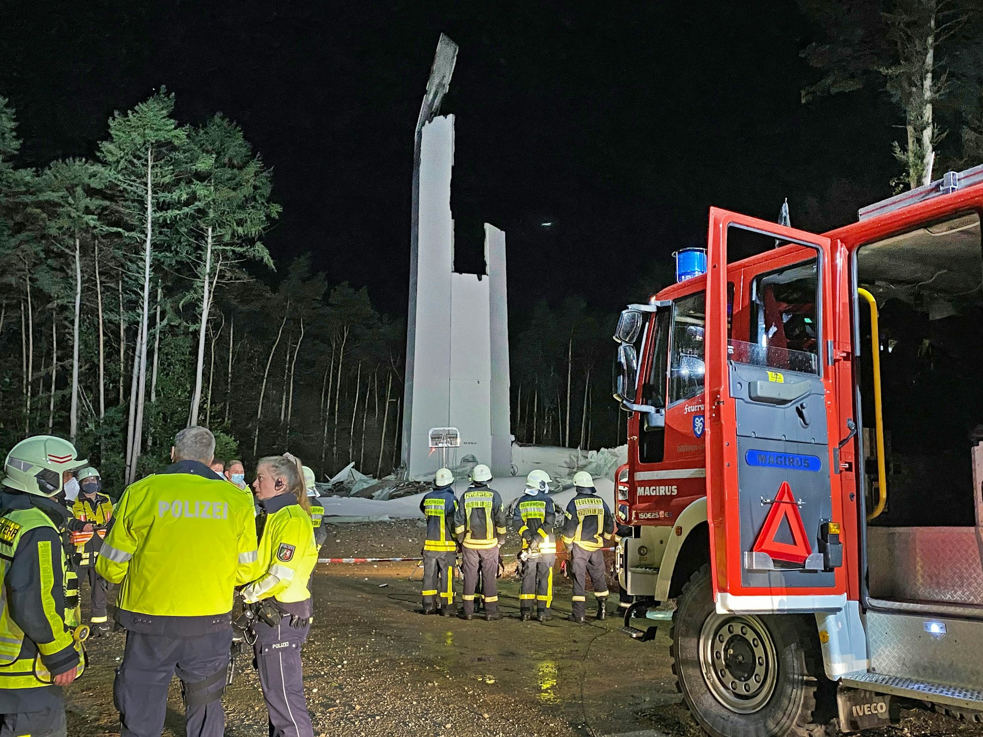 Feuerwehrleute und Polizisten stehen am 29. September 2021 vor den Resten des Turms eines Windrandes. Das fast 240 Meter hohe Windrad ist in sich zusammengestürzt.