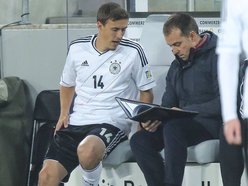 Max Kruse sitzt neben Hansi Flick auf der Auswechselbank der Nationalmannschaft.