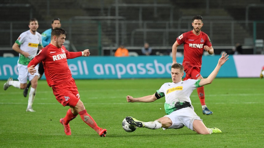 Borussias Matthias Ginter (r.) streckt sich im Rheinischen Derby im März 2020 vor Kölns Jan Thielmann (l.) nach dem Ball.