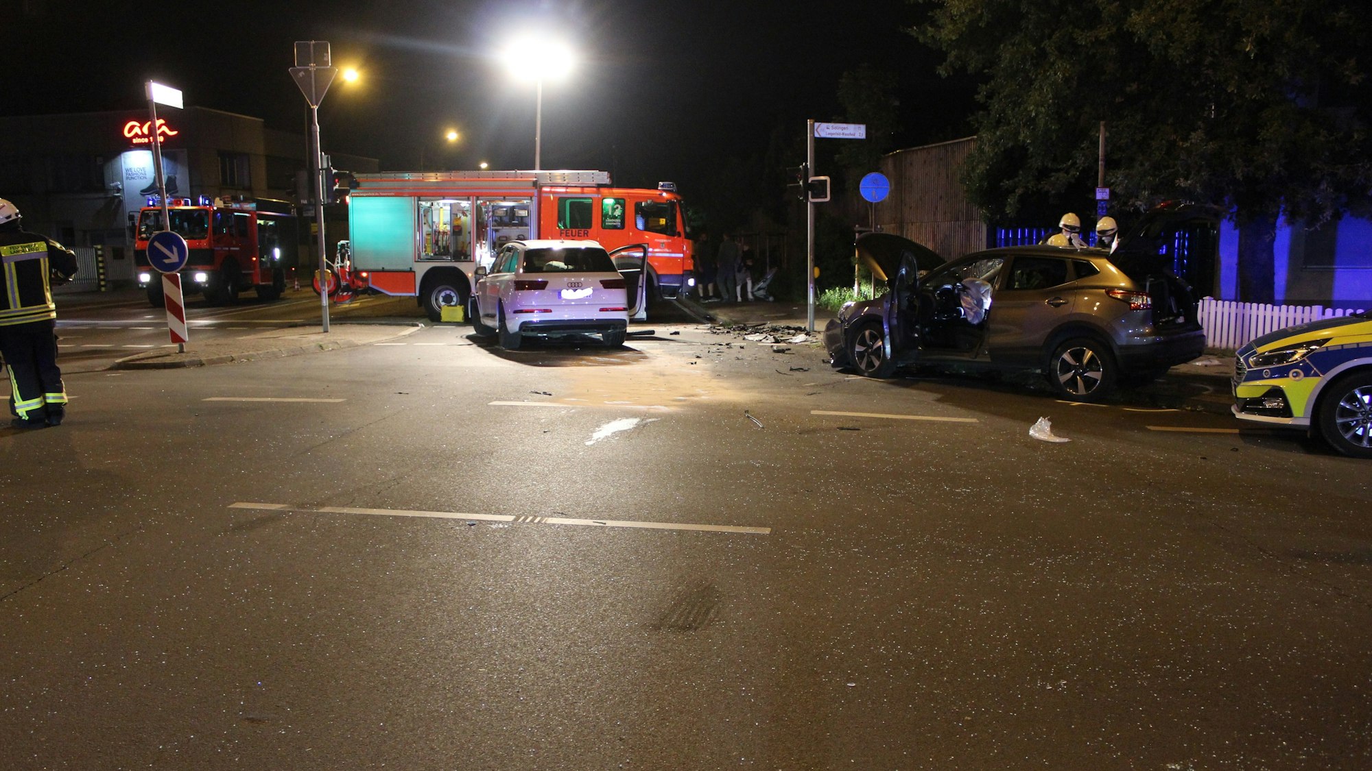 Zwei beschädigte Autos stehen auf der Kreuzung, Polizei und Feuerwehr sind im Einsatz.