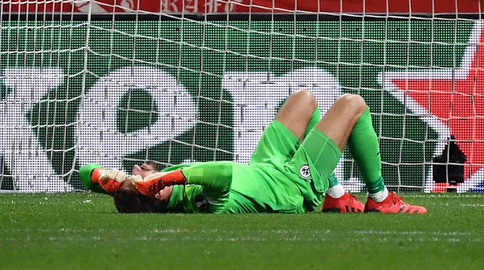 Kevin Trapp von Eintracht Frankfurt wurde von einem Böller der Zuschauer getroffen und liegt am Boden.
