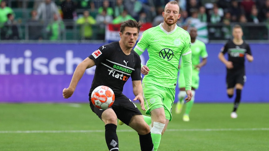 Jonas Hofmann (l.) von Borussia Mönchengladbach im Zweikampf mit Maximilian Arnold (r.) vom VfL Wolfsburg während des Bundesliga-Duells am 2. Oktober 2021 in der VW Arena. Hofmann hat den Ball vor sich.