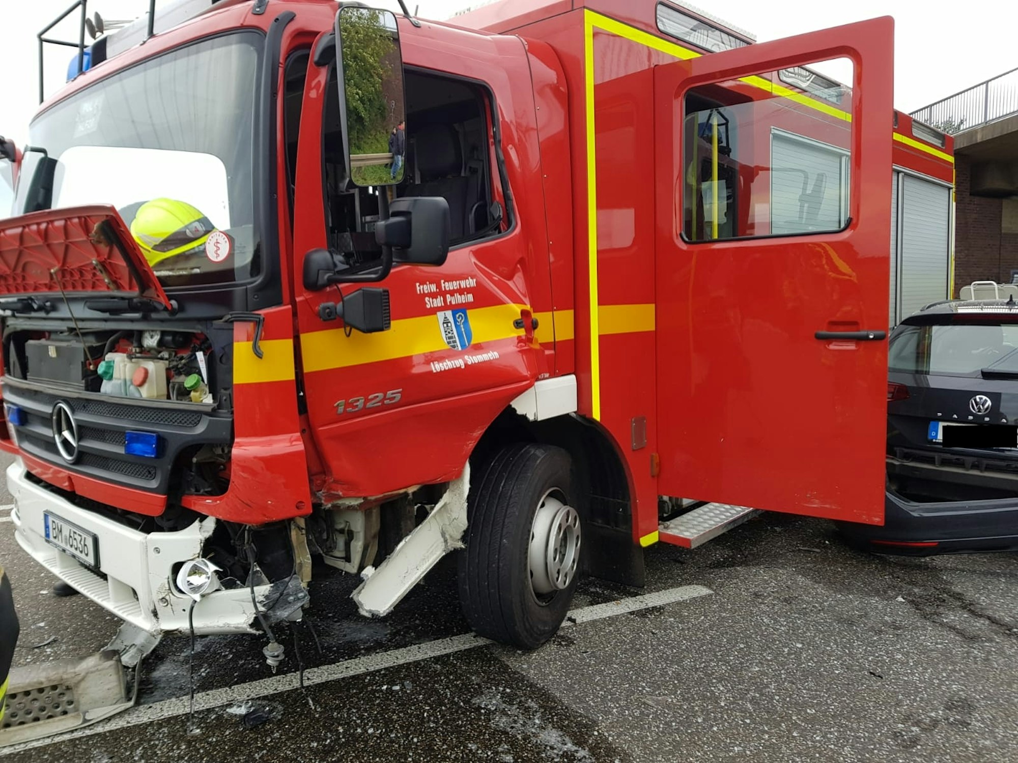 Ein Feuerwehrauto und ein ziviles Fahrzeug stehen nach einem Unfall beschädigt auf der Fahrbahn.