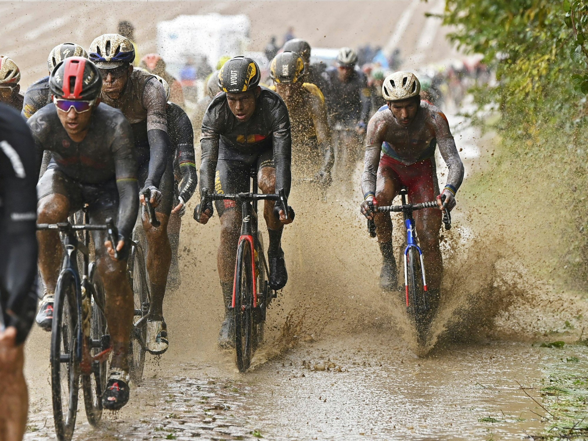 Beim Straßenrennen in Paris-Roubaix muss dasFahrerfeld durch eine große Schlamm-Pfütze.