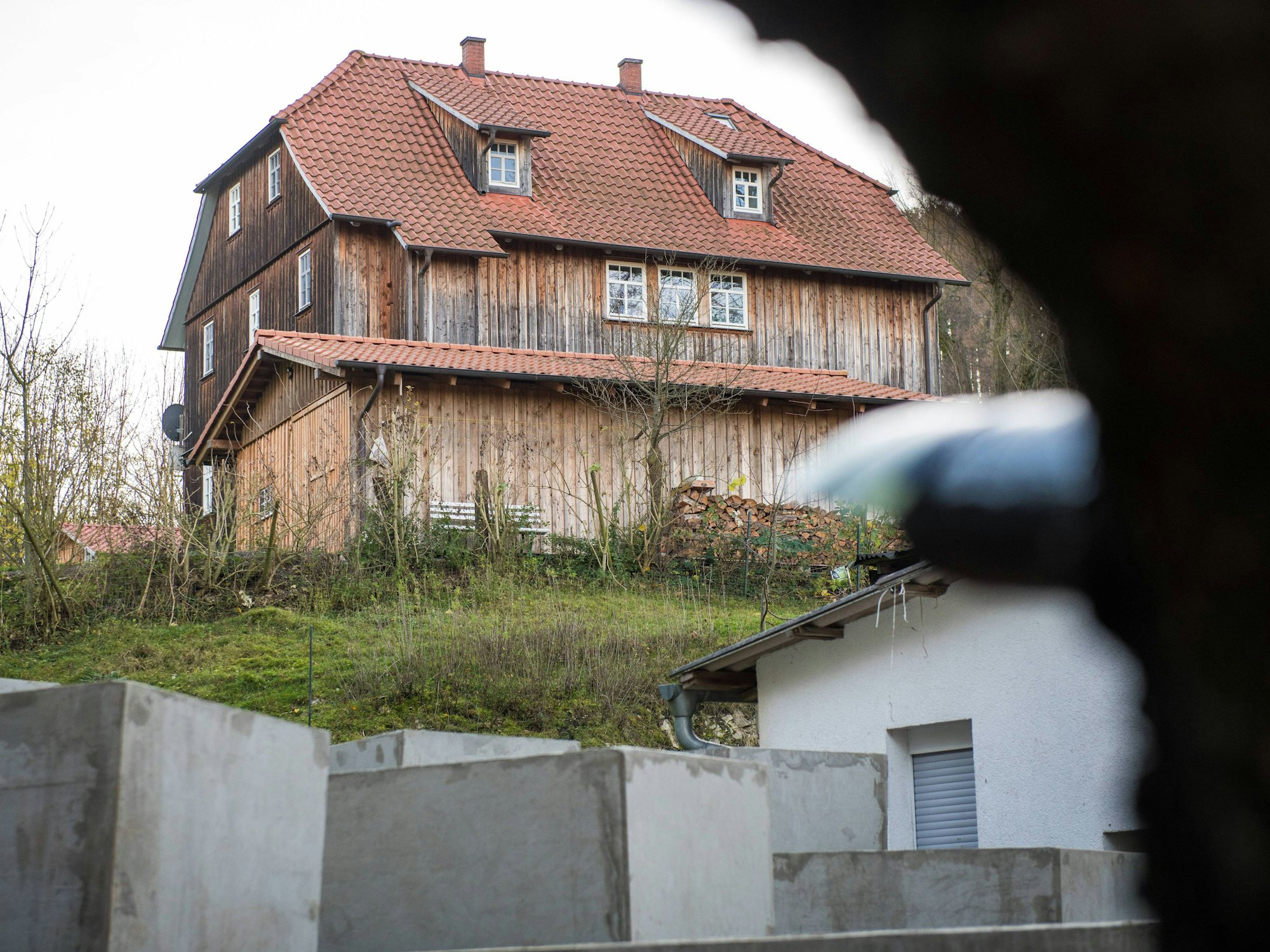 Im Hintergrund befindet sich Björn Höckes Haus, im Vordergrund sind Betonstelen zu sehen, die an das Holocaust-Mahnmal in Berlin erinnern.