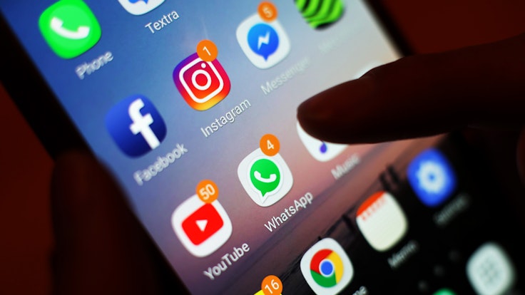 Ein Blick auf ein Smartphone mit den verschiedenen Social Media Apps, wie Facebook, Instagram, YouTube und WhatsApp.