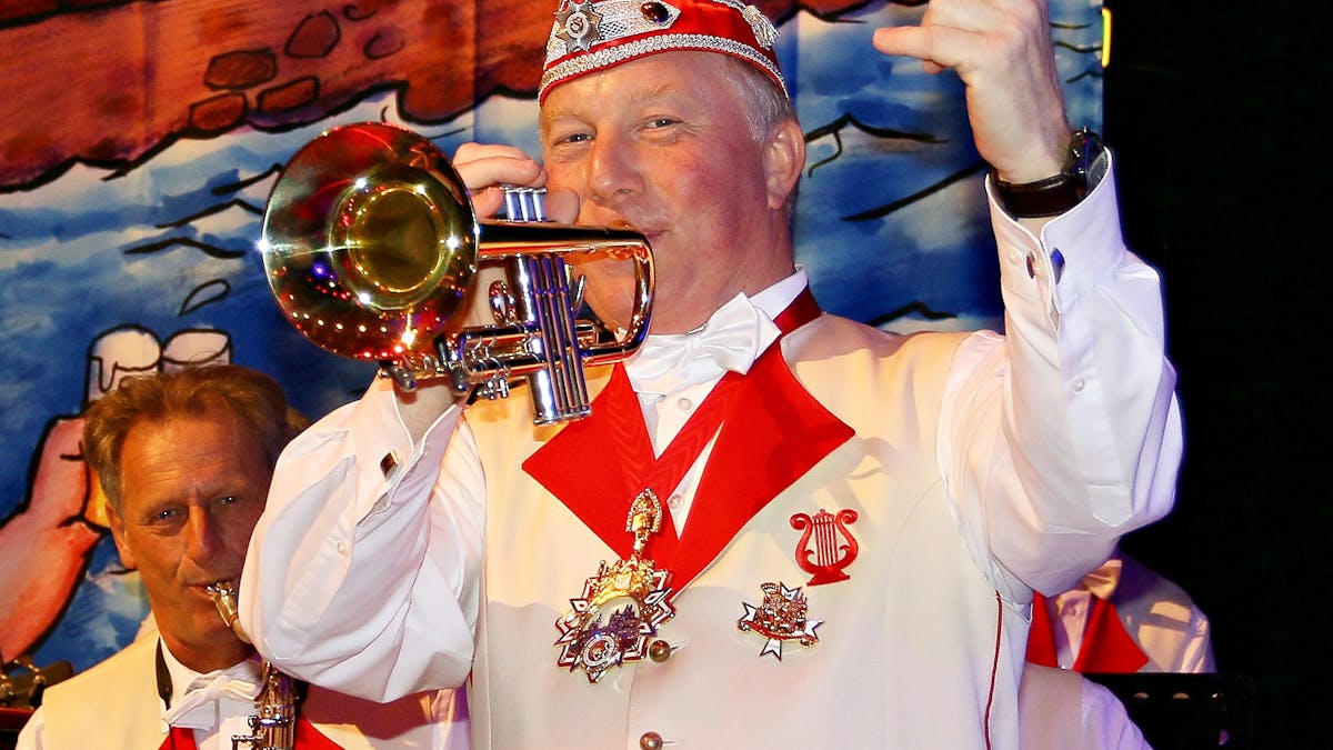 Helmut Blödgen spielt mit einer Hand Trompete, mit der anderen zählt er ein.