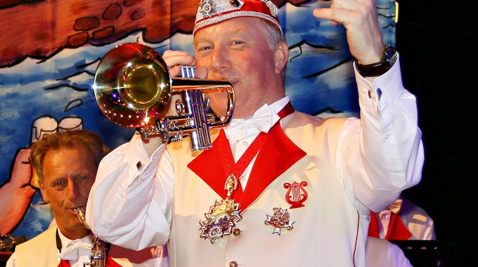 Helmut Blödgen spielt mit einer Hand Trompete, mit der anderen zählt er ein.