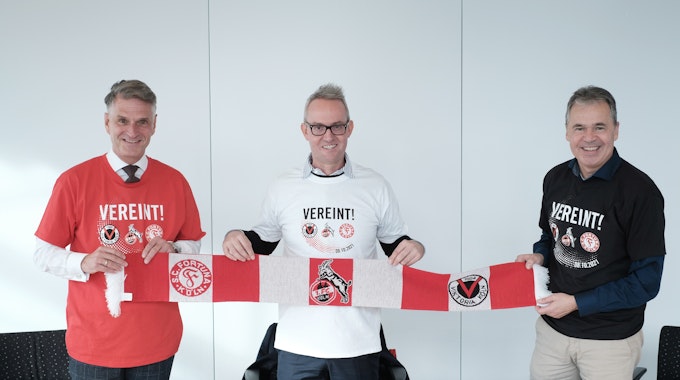Andreas Rettig, Alexander Wehrle und Hanns-Jörg Westendorf (v.r.) demonstrieren gemeinsam mit dem „Mottoschal“ und T-Shirt Einigkeit.