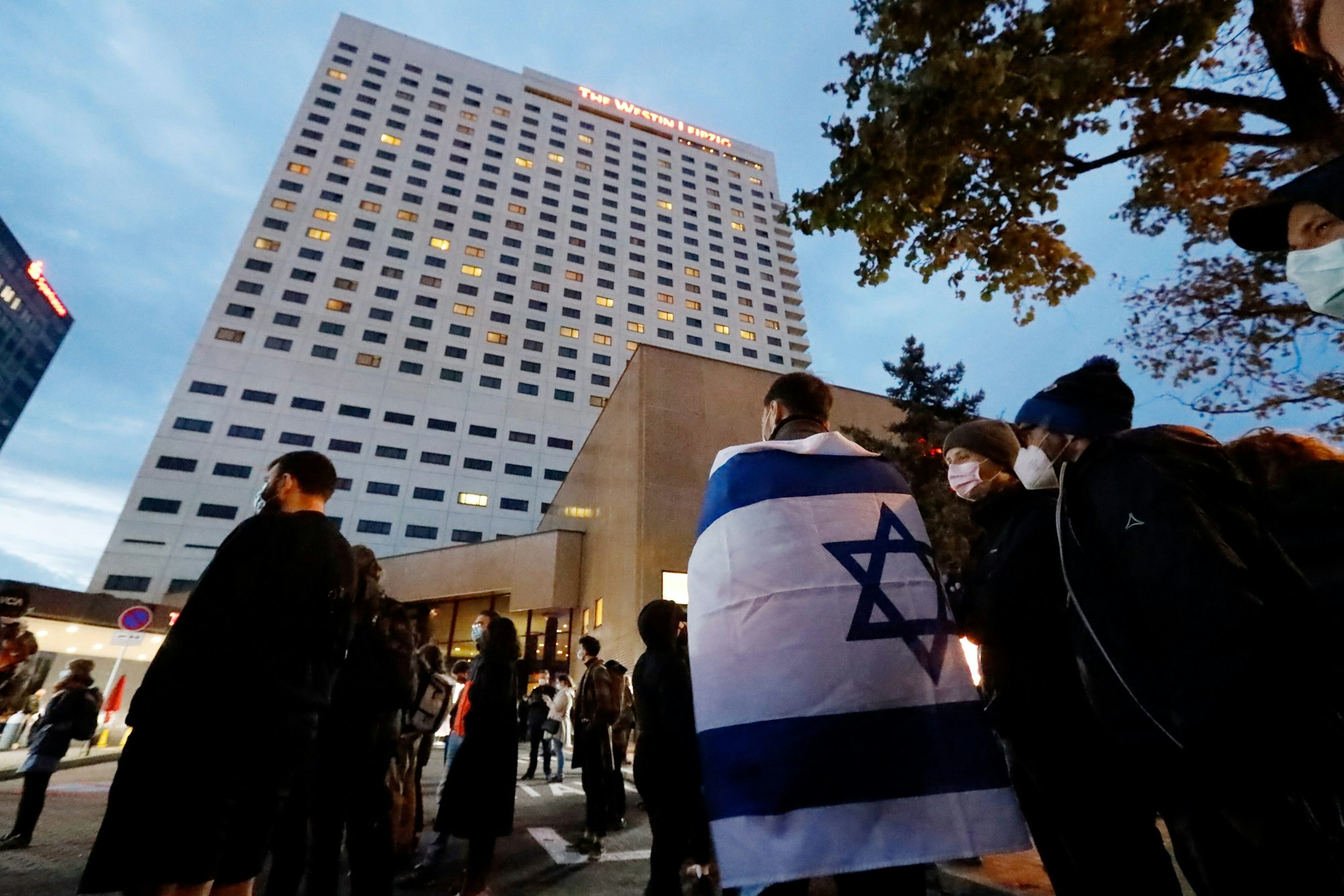 Ein Demonstrant trägt die Fahne Israels über den Schultern. Nach Antisemitismus-Vorwürfen haben sich am Abend Hunderte Menschen vor dem «Westin Hotel» Leipzig versammelt, um Solidarität mit dem Musiker Gil Ofarim und Jüdinnen und Juden in Deutschland zu zeigen.