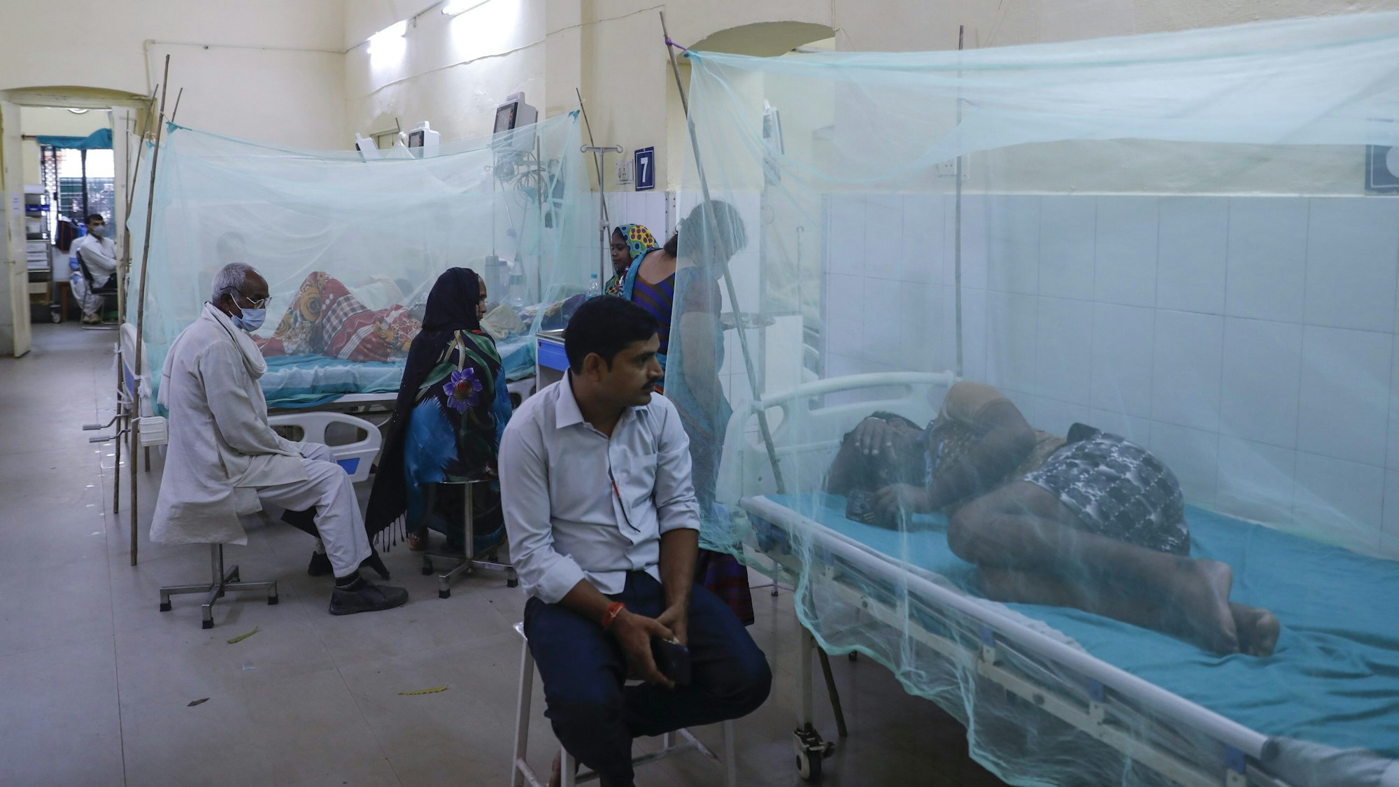 Die mit dem vom Mücken übertragenen Dengue-Fieber erkrankten Patienten liegen, von Mosquito-Netzen umhüllt, im Krankenhaus. Ärzte und Angehörige kümmern sich um die leidenden Menschen, können aber nicht viel ausrichten.