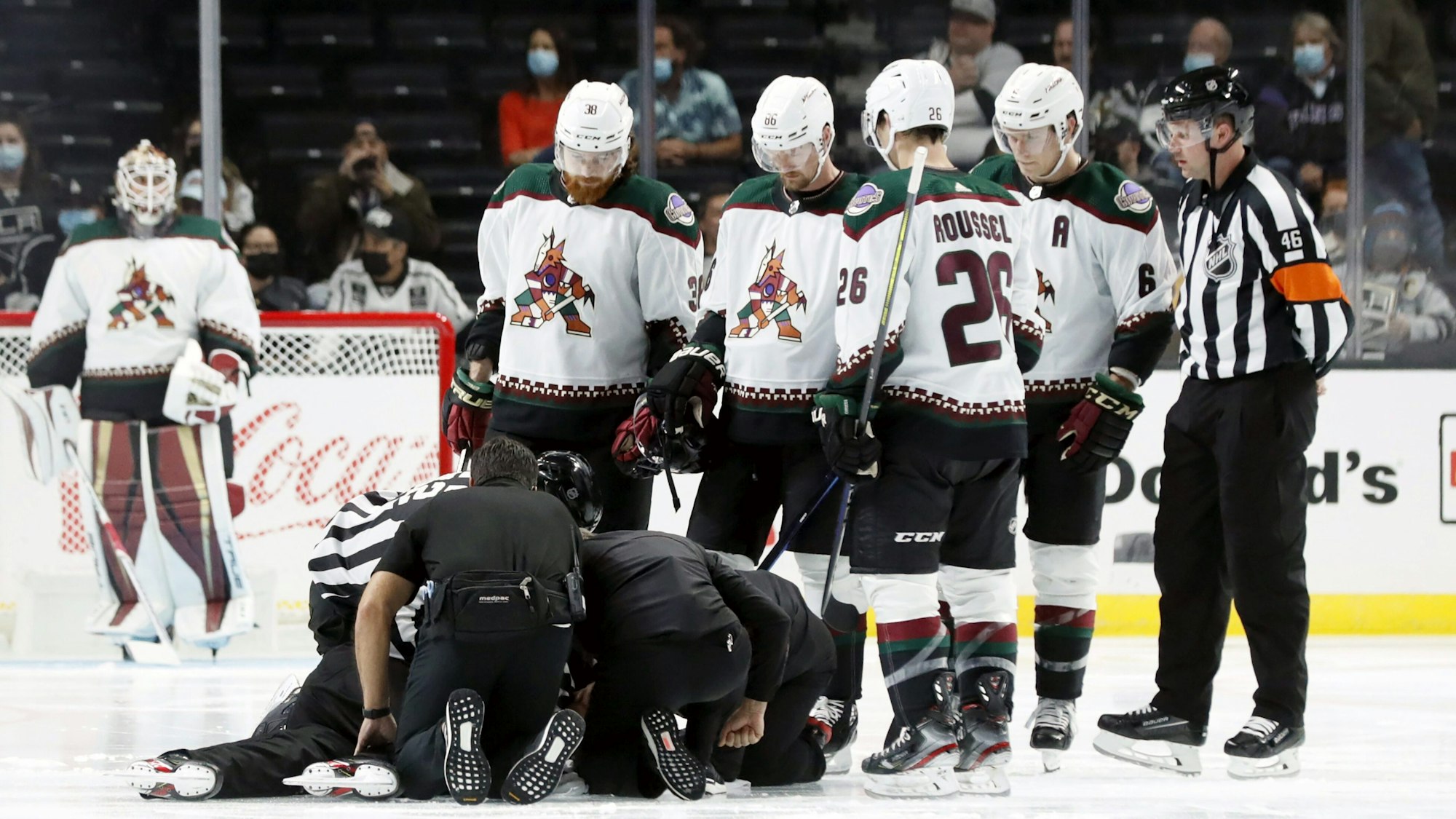 Die Spieler der Arizona Coyotes versammeln sich bei einem NHL-Vorbereitungsspiel um den am Boden liegenden Schiedsrichter Ryan Gibbons, der von Medizinern behandelt wird.