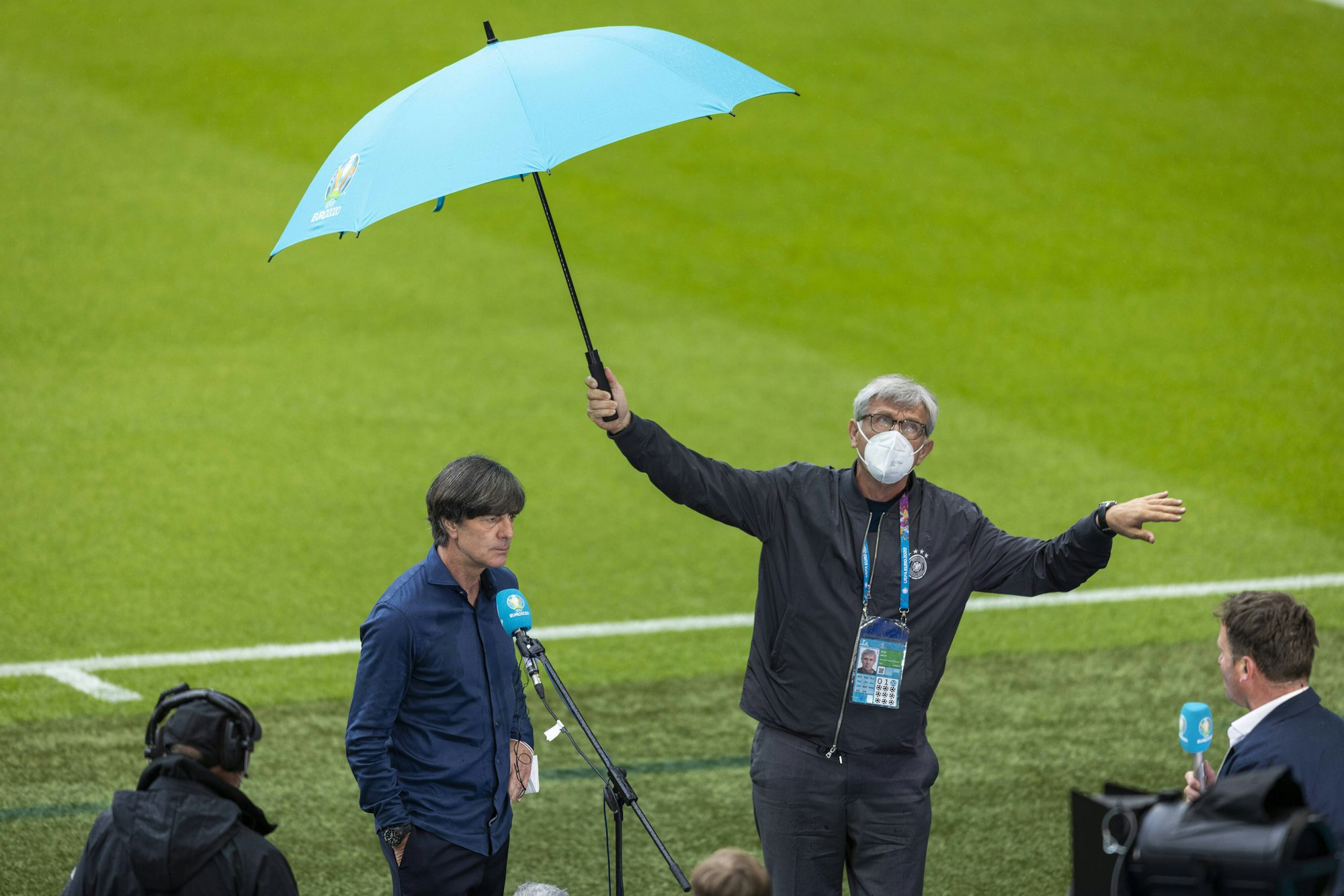 Joachim Löw gibt ein Interview, Uli Voigt hält den Schirm.